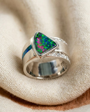 Vintage bright green and blue opal statement ring on cream textile, silver-tone band with diamond accents