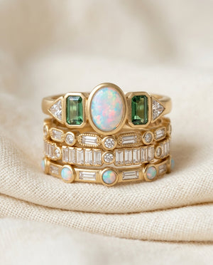 Vintage opal and zirconia stacking ring set on cream textile, four gold-tone bands with mixed-stone tops