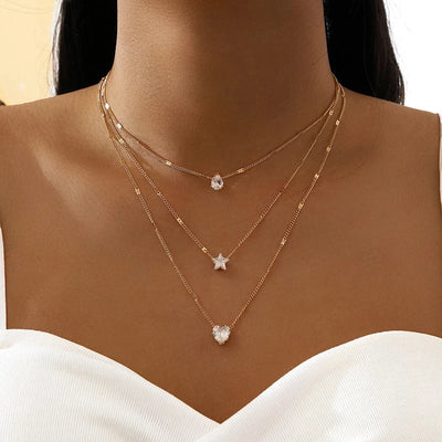 Fine gold chain with three small pendants at varying drop lengths. By Sophi.