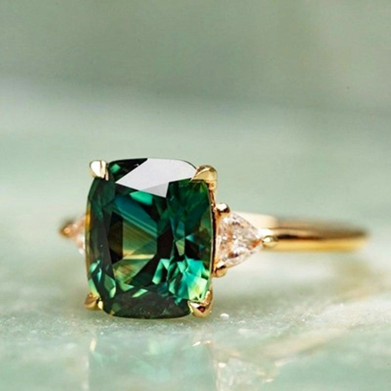 Gold ring with a green gemstone on a light green background