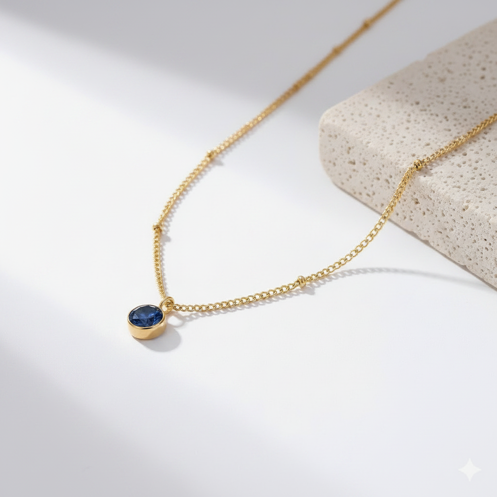 Gold necklace with a blue gemstone pendant on a light background