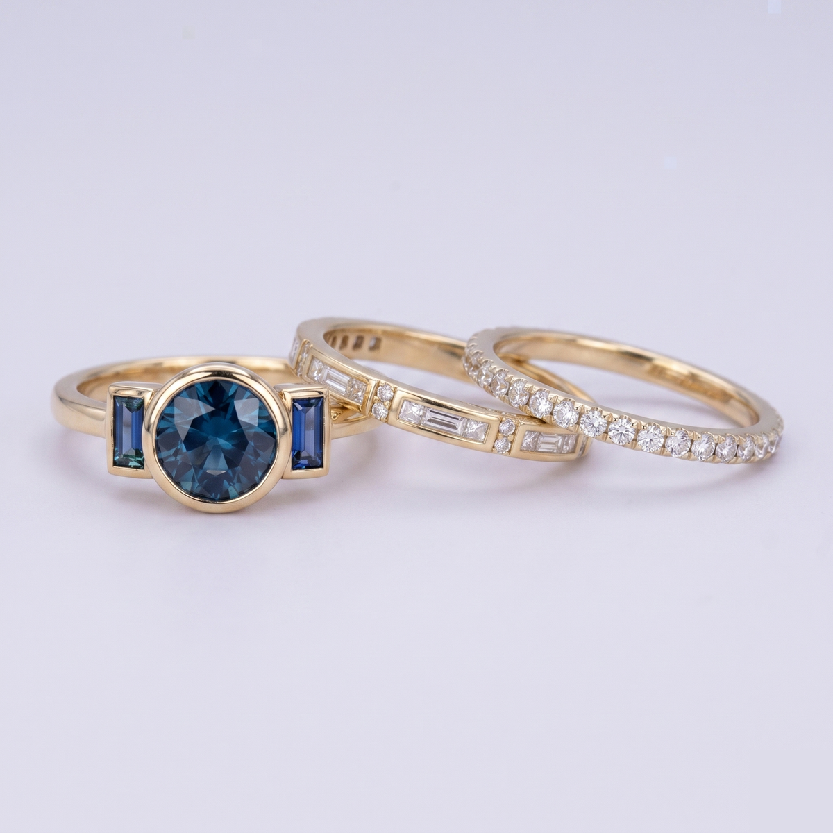 Three gold rings with gemstones on a light gray background