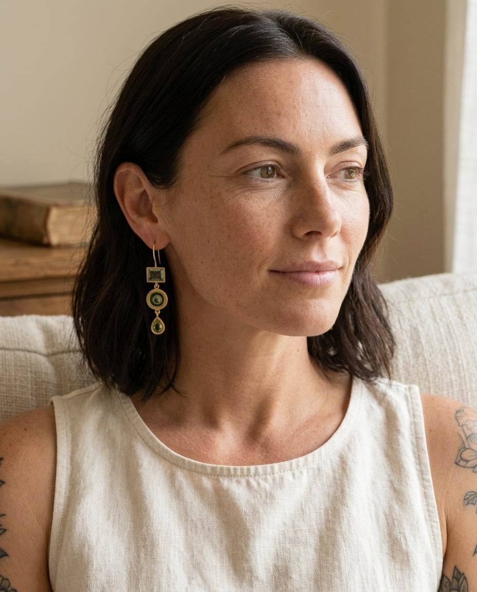 Vintage green dangling earrings on a brunette woman reading in a quiet nook