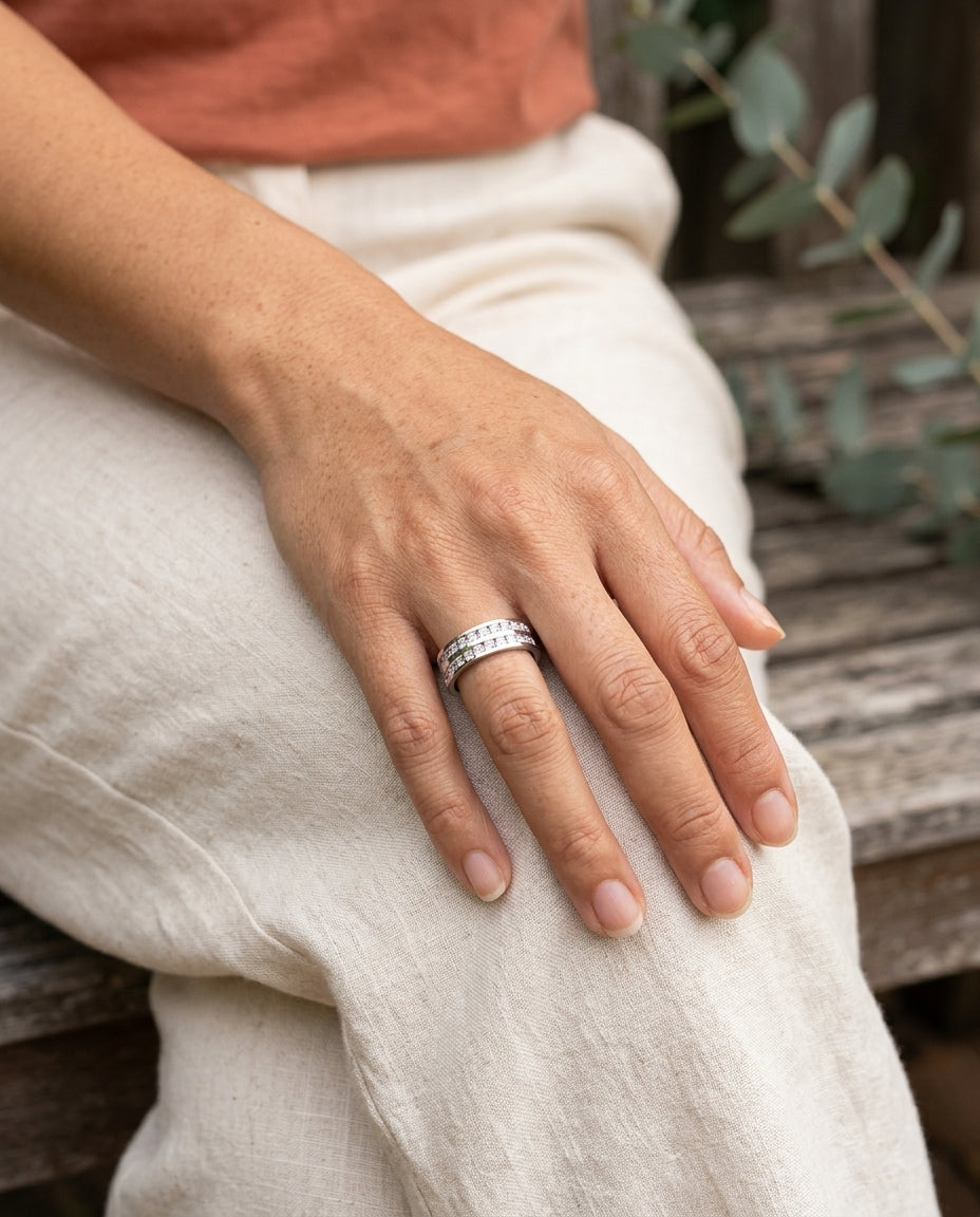 Elegant inlaid zirconia ring on hand resting on knee in a sunlit garden