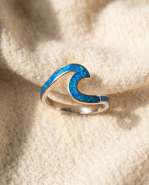 By Sophi Sea Wave Ring in Blue Opal & Silver flat-lay on warm cream wool