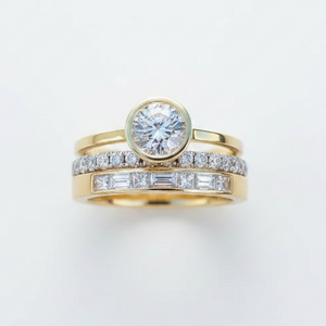 Gold ring with diamond and baguette stone on a light gray background